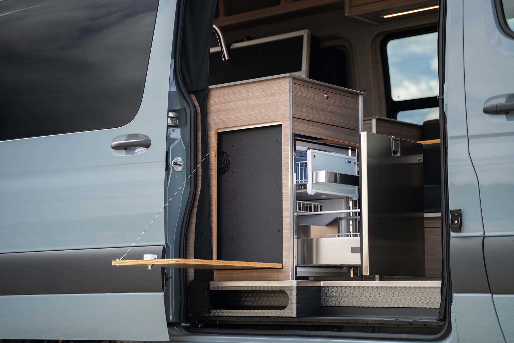 The fold-down exterior table and outdoor kitchen access on the Metis camper van