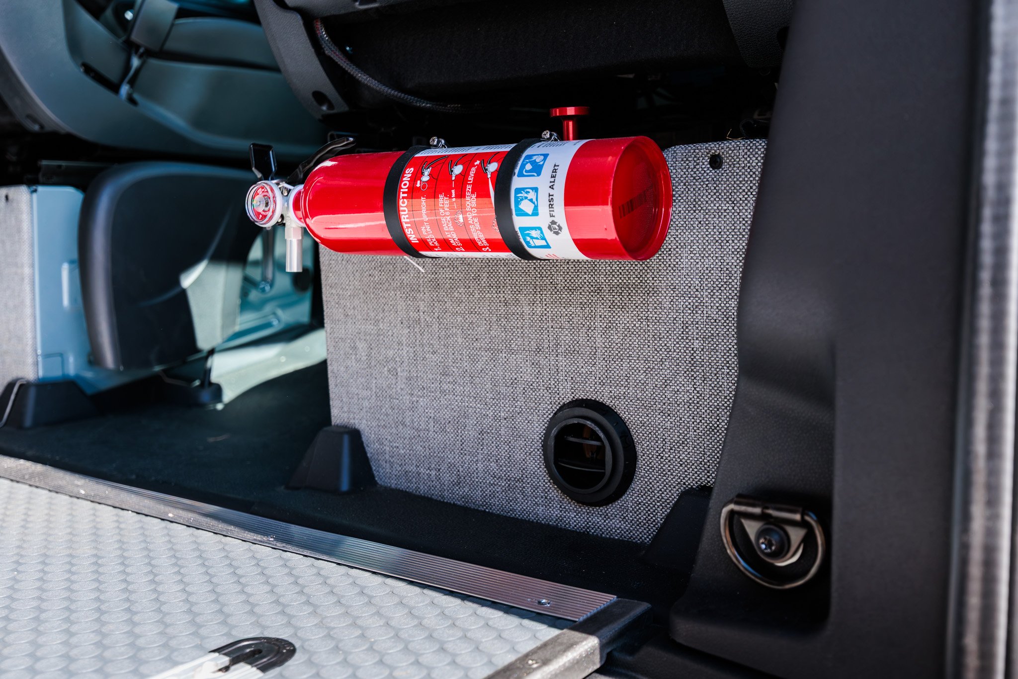 Fire extinguisher mounted on the cab bulkhead panel