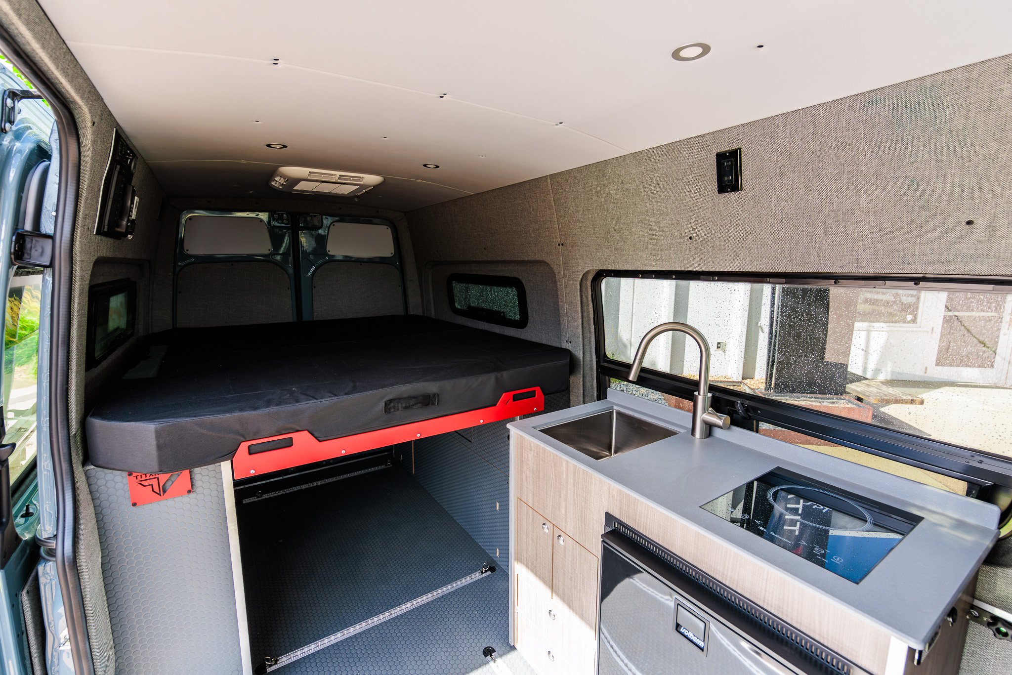 Classic 144 interior looking rear — the bi-slide aluminum bed made up over the garage, galley in the foreground
