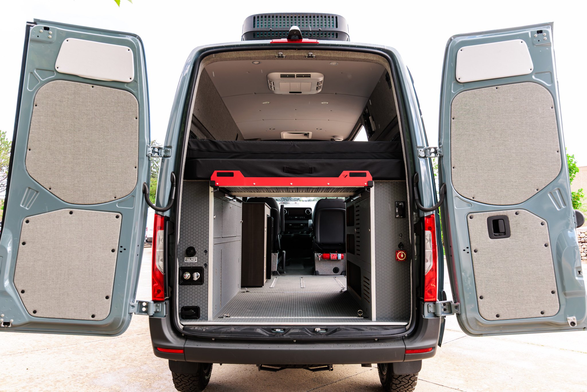 Blue Gray camper van from the rear with both doors open on the galley and bed