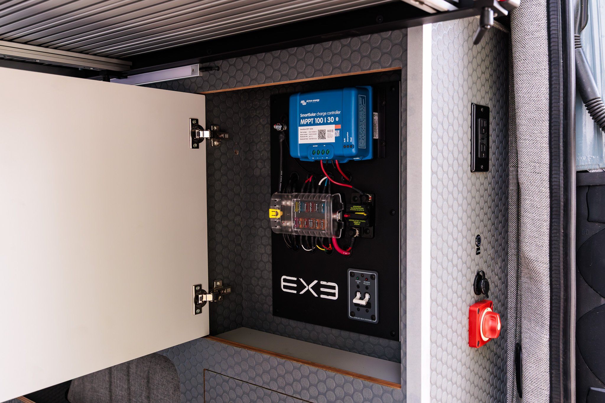 Cabinet open on the Victron SmartSolar MPPT 100/30 charge controller and the fuse panel