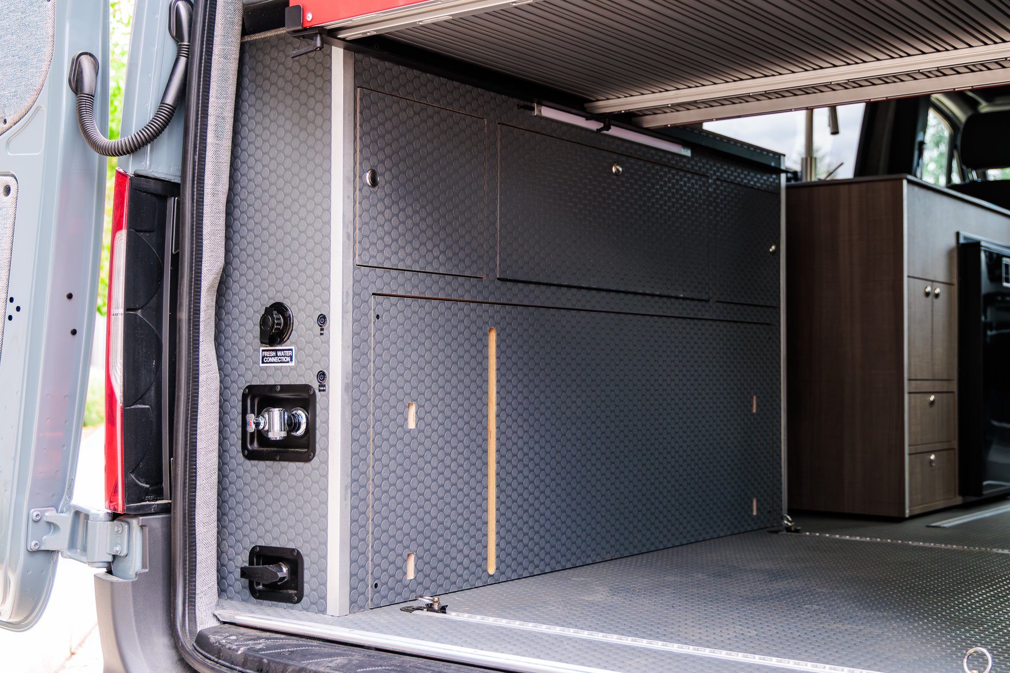 Rear garage under the bi-slide bed, cabinets closed, seen through the open rear doors