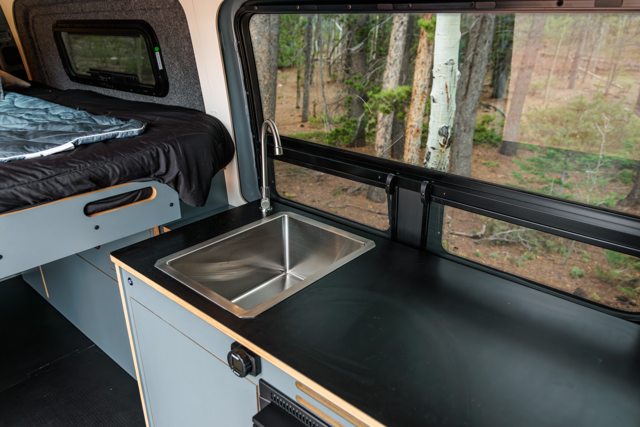 Galley sink and black countertop beside the slider door window