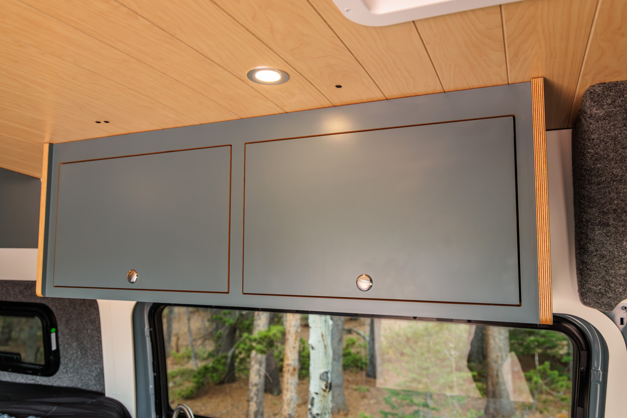 Overhead cabinets in dark blue laminate above the side window