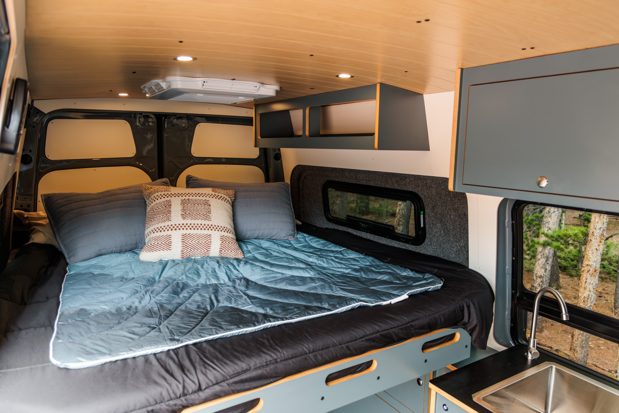 Bed and overhead cabinets looking rearward, with the rooftop air conditioner above