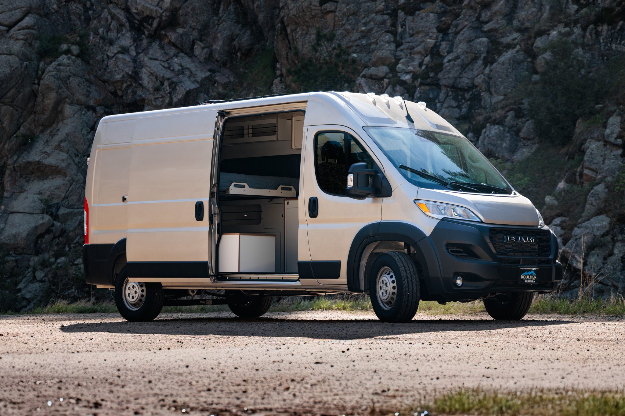Timber Camp van — sandstone Ram ProMaster exterior parked on a gravel pull-off with the sliding door open
