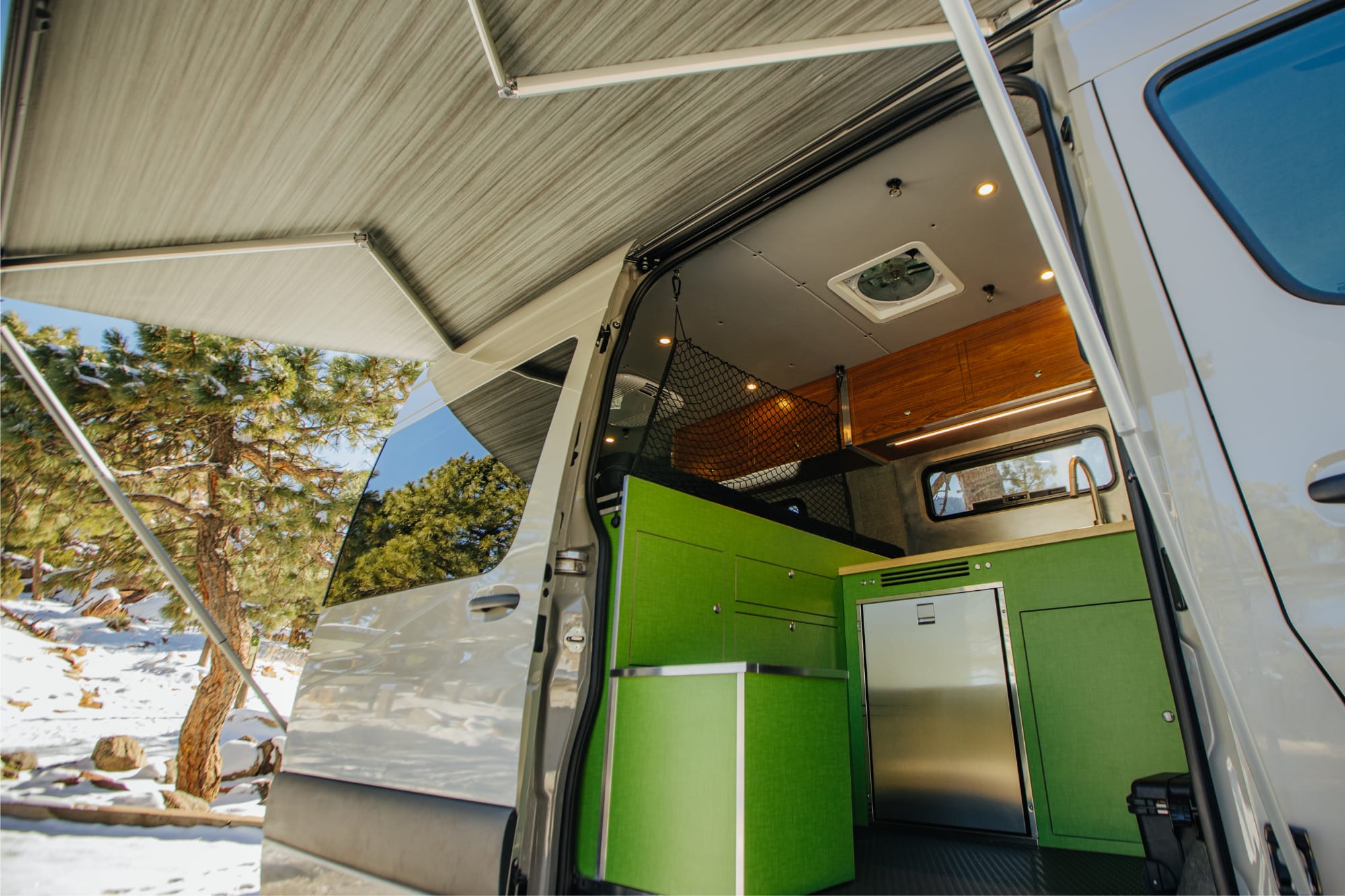 A close-up view into a camper van through the side door. All the cabinetry is bright green.