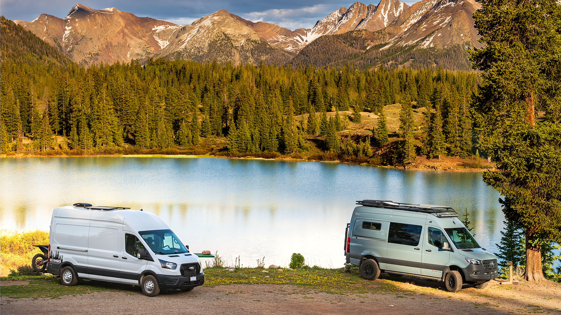 Ford Transit and Mercedes Sprinter camping next to a lake.